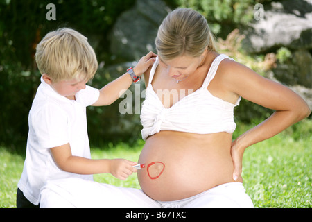 Ragazzo (4-5 anni) disegno sul cerchio della donna incinta, ventre, Stiria, Austria Foto Stock