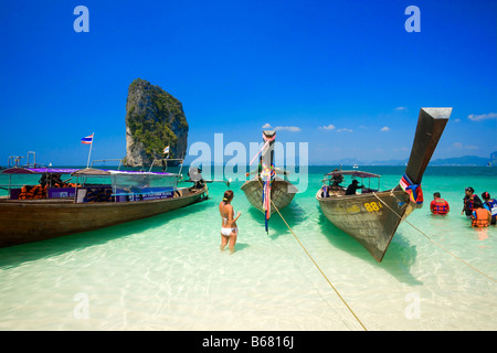 Barche ancorate alla spiaggia, i turisti con i giubbotti di salvataggio in piedi in acqua, Ko Poda in background, Laem Phra Nang, Railay, Krabi, tailandese Foto Stock