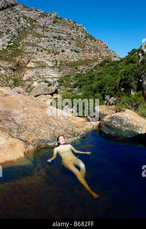 La donna a prendere il sole in piscina di roccia Foto Stock