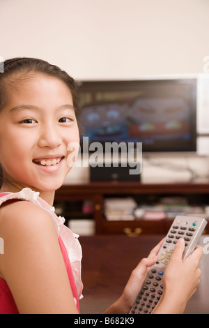 Ritratto di una ragazza con un telecomando e sorridente Foto Stock