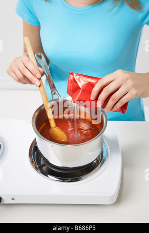 Donna aggiunta di pectina di salsa al peperoncino per rendere Jelly Foto Stock
