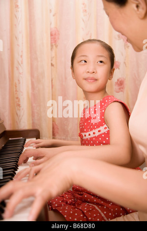 Donna matura insegnamento suo nipote come riprodurre un pianoforte Foto Stock