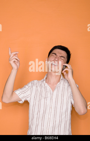 Maschio di lavoratore di ufficio a parlare su un telefono mobile e guardando scioccato Foto Stock