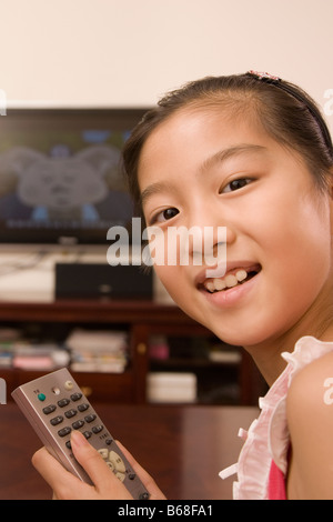 Ritratto di una ragazza con un telecomando e sorridente Foto Stock