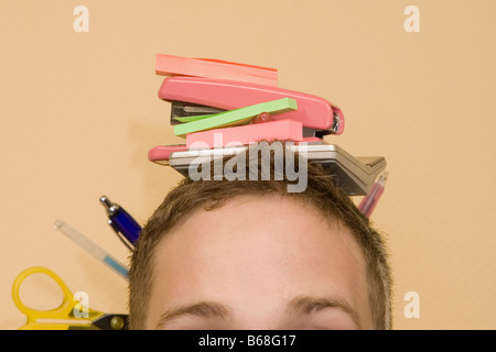 Close-up di un giovane uomo con gli oggetti di cancelleria sulla sua testa Foto Stock