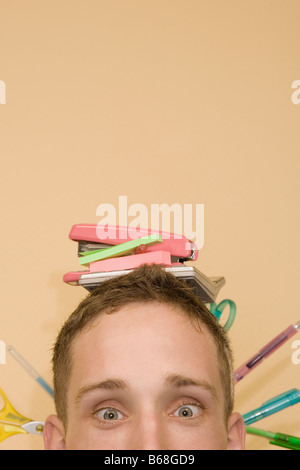 Close-up di un giovane uomo con gli oggetti di cancelleria sulla sua testa Foto Stock