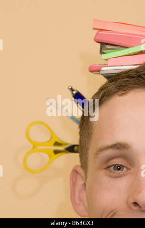 Close-up di un giovane uomo con gli oggetti di cancelleria sulla sua testa Foto Stock