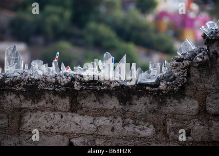 Bottiglia cocci cementato sulla sommità di un muro di mattoni per fornire bassi tech sicurezza da ladri Foto Stock