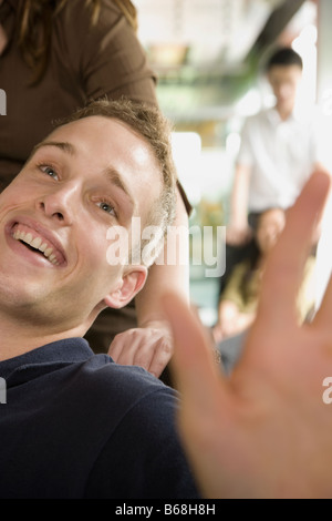 Metà vista in sezione di una giovane donna spingendo un giovane uomo seduto su una sedia Foto Stock