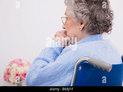 Senior donna seduta in carrozzella Foto Stock