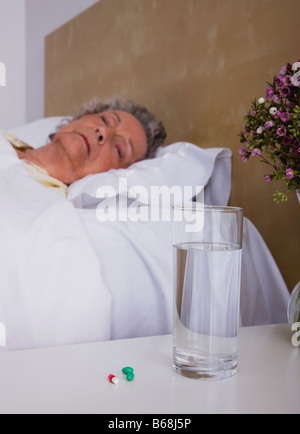 Senior donna dorme nel letto Foto Stock