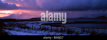 Buia e tempestosa inverno tramonto nevoso Cuillin Hills, da Breakish, Isola di Skye, Ebridi, Scotland, Regno Unito. Foto Stock