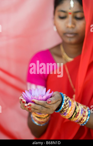 Donna indiana offre un Nymphaea ninfea tropicale fiore in un sari rosso. Andhra Pradesh, India Foto Stock