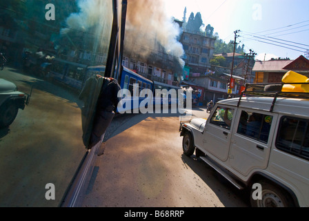 "Toy Train' del Darjeeling Himalayan Railway si snoda in mezzo al traffico stradale sulle strade di Darjeeling Foto Stock