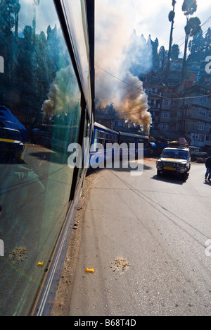 "Toy Train' del Darjeeling Himalayan Railway si snoda in mezzo al traffico stradale sulle strade di Darjeeling Foto Stock