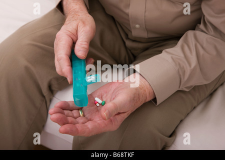 Senior uomo pillole di colata dalla pillola settimanale distributore, close-up delle mani Foto Stock