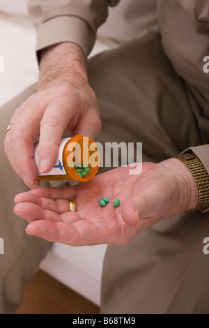 Senior uomo pillole di colata dalla pillola bottiglia, close-up delle mani Foto Stock