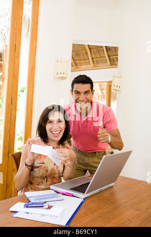Coppia sorridente davanti a un computer portatile Foto Stock