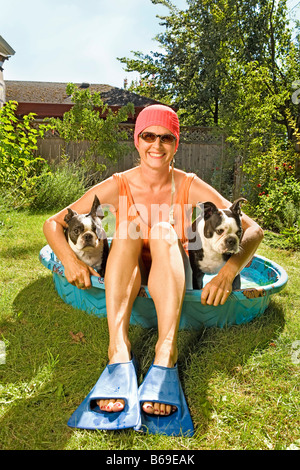 Donna seduta in una piscina per bambini con due Boston Terrier Foto Stock