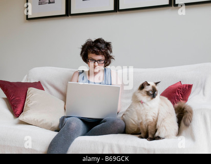 Femmina tenendo un gatto e un computer portatile Foto Stock