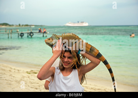 Messico. Majahuala. Quintana Roo, donna sulla spiaggia con iguana con la nave di crociera in background. Foto Stock