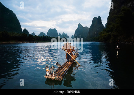 Pescatore in piedi su una zattera di legno in un fiume, il Fiume Li, XingPing, Yangshuo, provincia di Guangxi, Cina Foto Stock