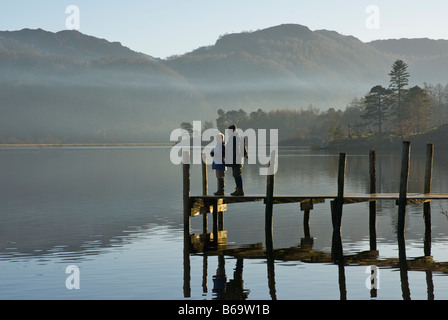 Due escursionisti in piedi sul molo Brandelhow, Derwent Water, Parco Nazionale del Distretto dei Laghi, Cumbria, England Regno Unito Foto Stock