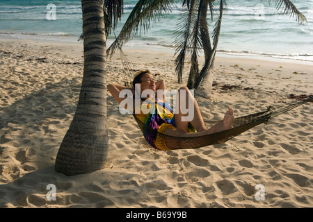 Messico, Quintana Roo, Tulum, turistico (donna) in amaca sotto le palme in spiaggia Foto Stock