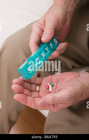 Senior uomo pillole di colata dalla pillola settimanale distributore, close-up delle mani Foto Stock
