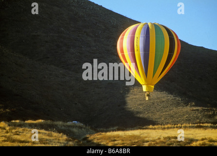 In mongolfiera ad aria calda si sposta al di sopra di collina come si prepara a terra. Foto Stock