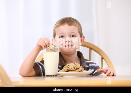 Ragazzo giovane mettendo cookie nel latte Foto Stock
