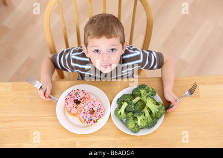 Ragazzo con piastre di broccoli e ciambelle Foto Stock