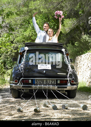 Sposa e lo sposo sventolare dalle auto di nozze Foto Stock