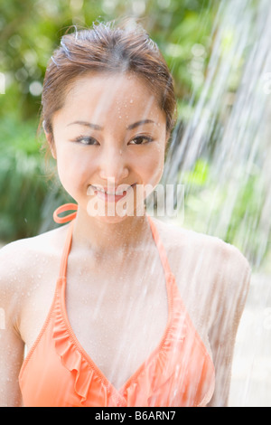 Giovane donna in bikini tenendo doccia Foto Stock