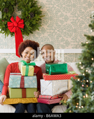 Coppia africana nel soggiorno holding di pile di regali di Natale Foto Stock