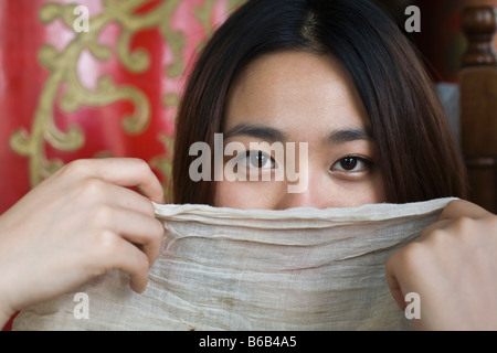 Donna cinese si nasconde dietro una sciarpa Foto Stock