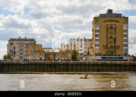 Una persona in kayak sul fiume Tamigi passato appartamento di lusso di blocchi Foto Stock