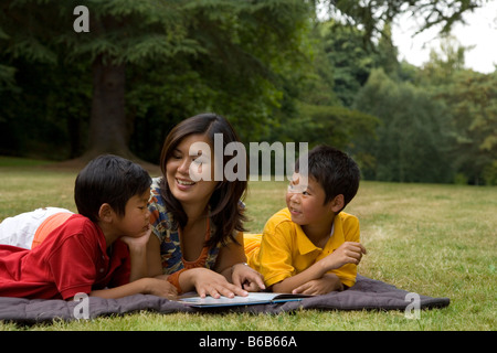 Asian madre libro di lettura ai figli in posizione di parcheggio Foto Stock