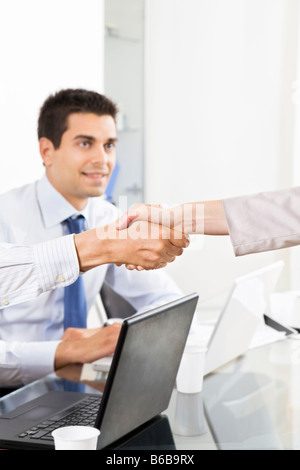 Imprenditore e la donna si stringono la mano in ufficio con il collega guardando Foto Stock