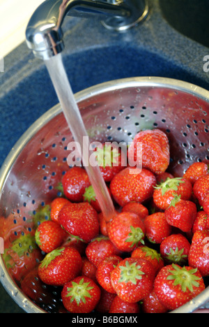 Close-up di fragole nel colapasta con rubinetto Foto Stock