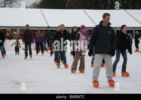 Persone che si tengono per mano il pattinaggio su ghiaccio su una pista di pattinaggio all'aperto in serata in Windsor, Berkshire, Inghilterra Foto Stock