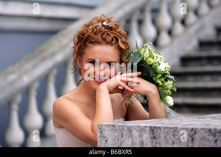 Mezzo corpo ritratto di sorridere auburn sposa azienda bouquet di nozze Foto Stock