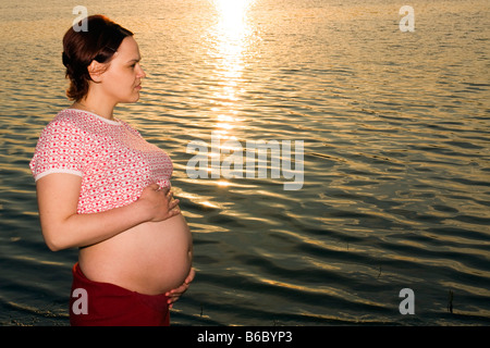 Donna incinta 28 anni e tramonto al di fuori Foto Stock
