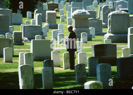 Donna matura con noi il flag nel cimitero Foto Stock