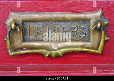 Un antico ottone letter box in una porta rossa Foto Stock