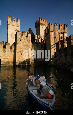 Castello Scaligeri a Sirmione con pescatori barca in acqua anteriore. Il lago di Garda, Italia Foto Stock