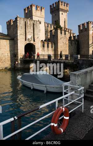 Castello Scaligeri a Sirmione con pescatori barca in acqua anteriore. Il lago di Garda, Italia Foto Stock