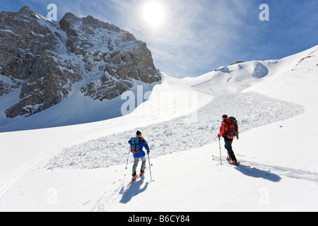 Vista posteriore, due sciatori a piedi con gli sci sulla montagna snowcovered Knallstein Tennengebirge Schneebrett Tennengau Salisburgo in Austria Foto Stock