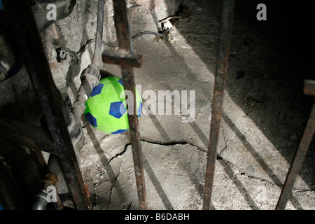 Un bambino di plastica del pallone da calcio dietro le sbarre in un edificio in rovina in Messico. Foto Stock