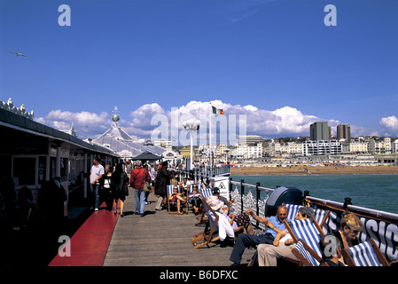 Persone in rilassanti sedie a sdraio sul molo di Brighton, Sussex, Inghilterra Foto Stock